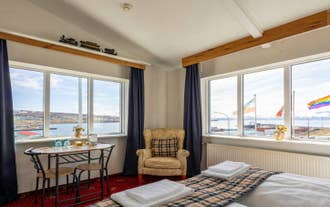 Suite lounge with a table by wide windows facing Skjalfandi Bay in Husavik, North Iceland.