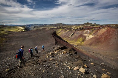 A hiking group walks along the dramatic mountainous landscape of the Highlands in Iceland.