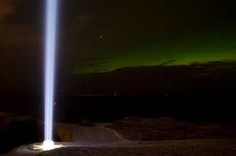 The Imagine Peace Tower against the green aurora borealis.