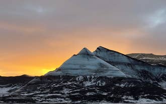 Solen går ned over nogle snedækkede tinder på Myrdalsjökull-gletsjeren.