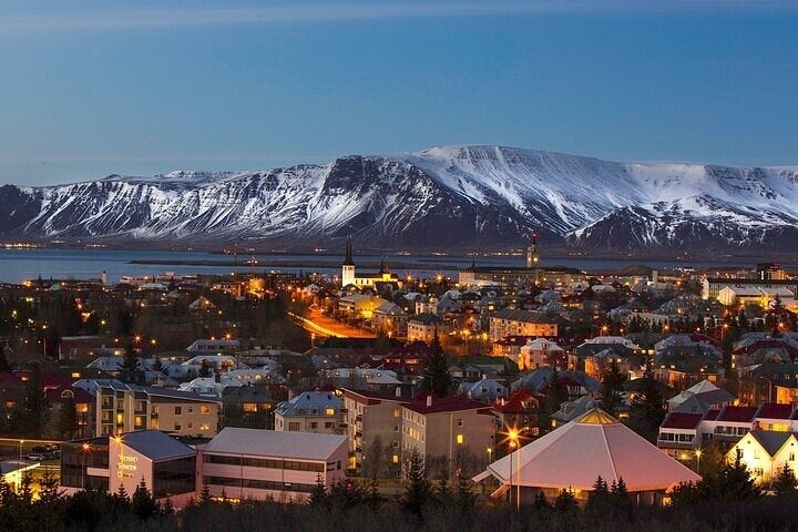 Una vista su Reykjavik di notte con le montagne innevate sullo sfondo