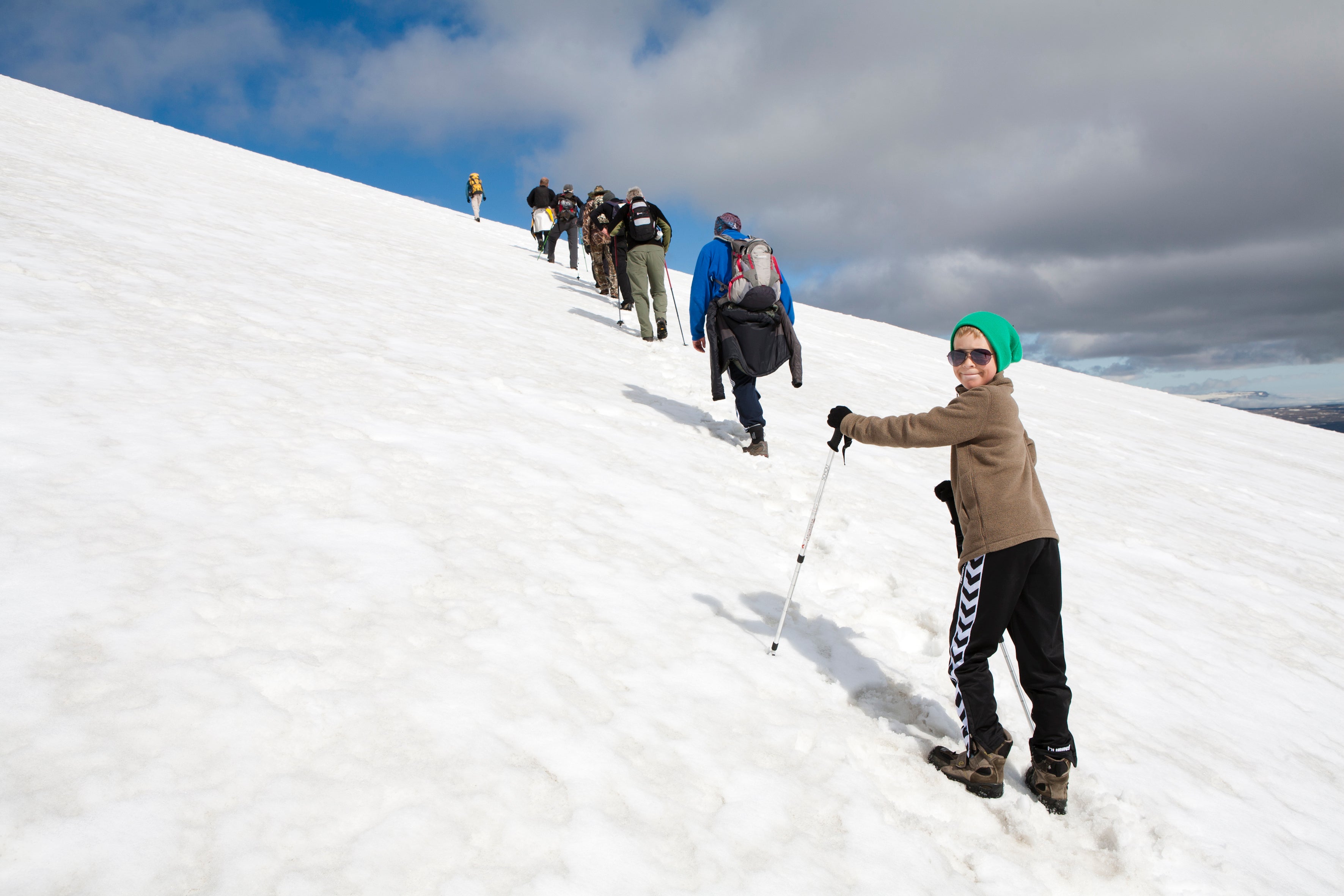 A group of people hiking up the snowy Snaefell mountain