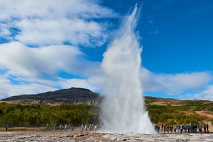 The Strokkur geyser in the Geysir geothermal area erupts, sending hot water high into the air.