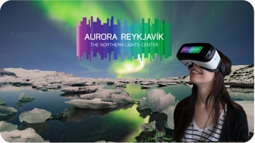 A woman wearing a VR headset looks upwards at Aurora Reykjavik.