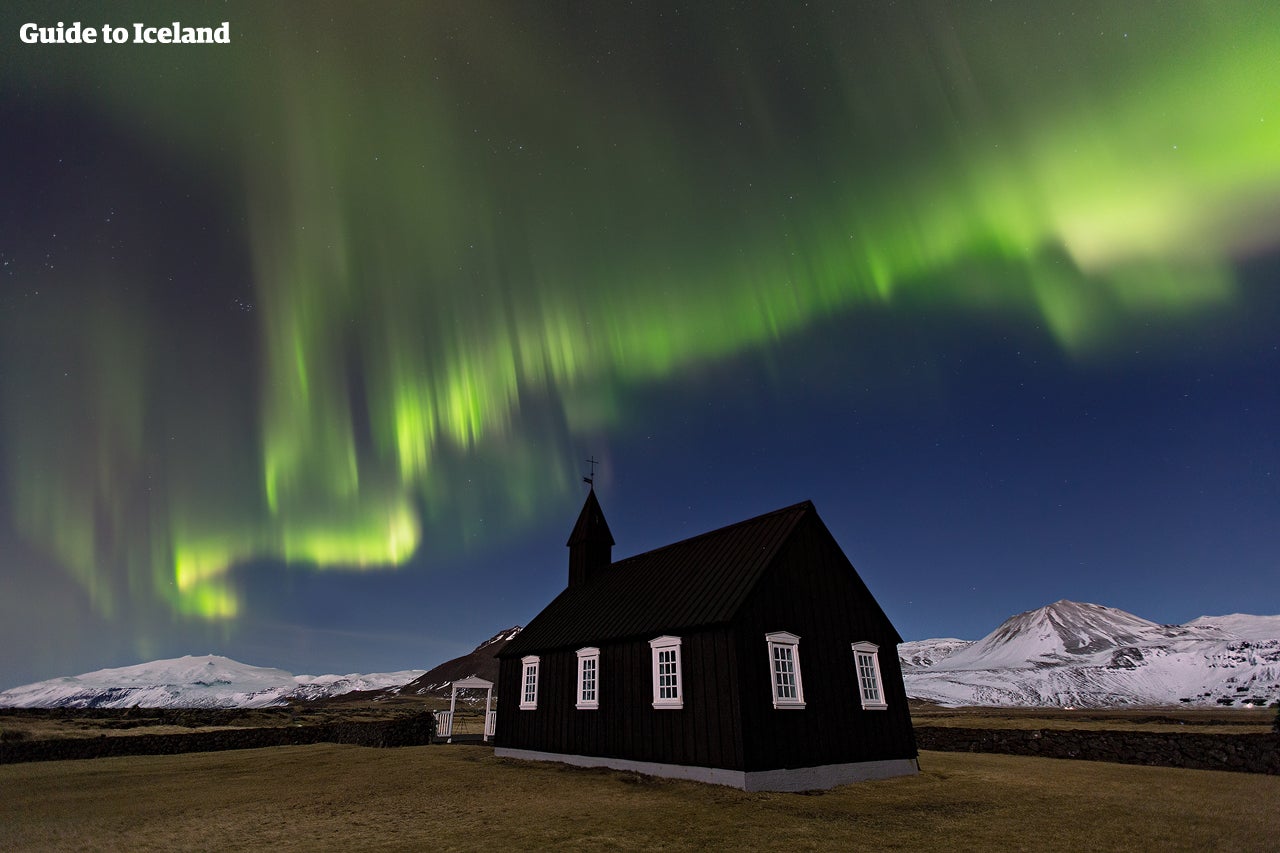 Het noorderlicht danst boven de zwarte kerk bij Búðir op het schiereiland Snæfellsnes