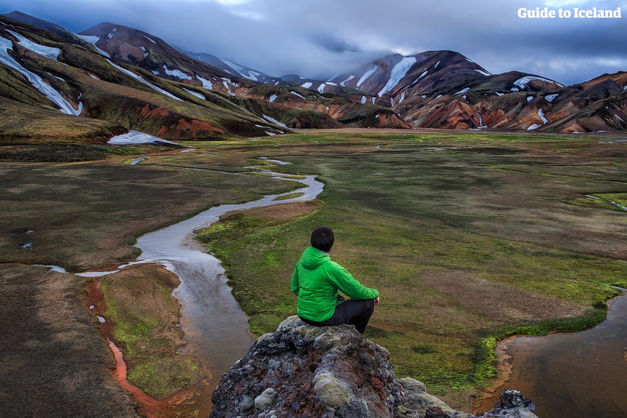 Mężczyzna siedzący i patrzący na krajobraz w Landmannalaugar.