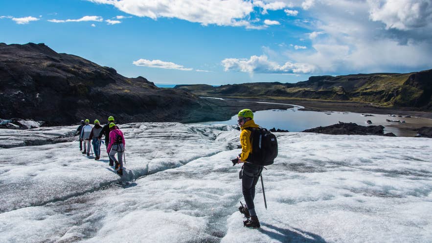 Eine Gruppe von Wanderern auf einem isländischen Gletscher, ausgestattet mit Helmen und Steigeisen bei einer geführten Gletscherwanderung.