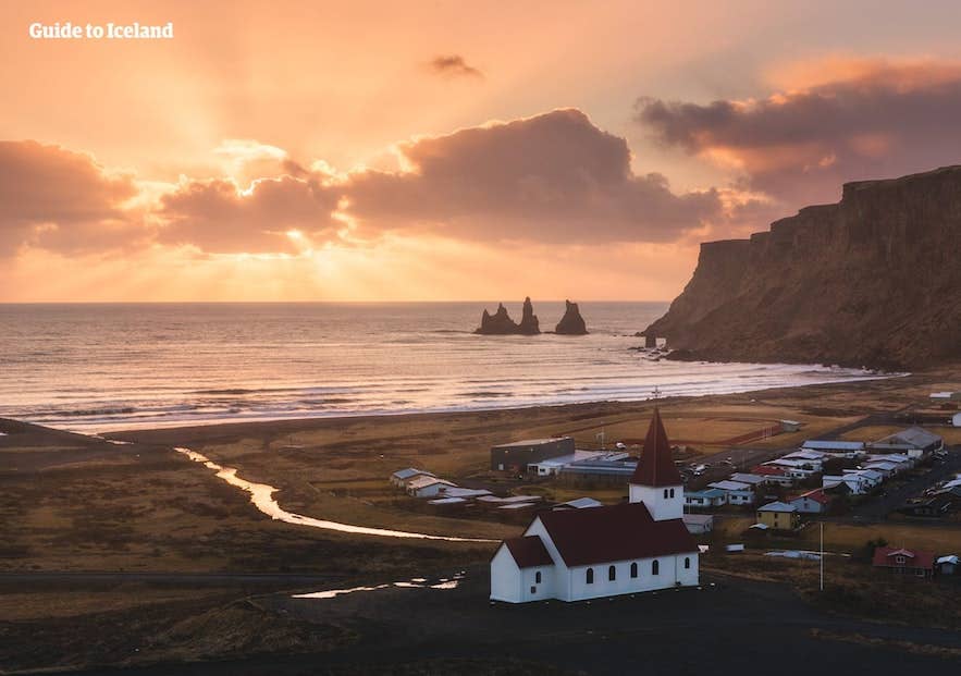 The white Vikurkirkja church with a red roof above the town of Vik on the South Coast