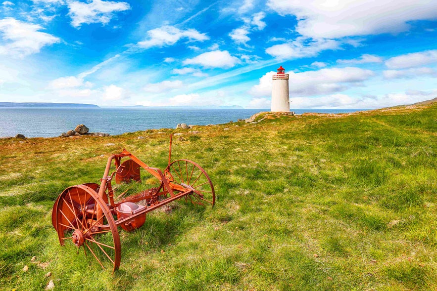 A historic lighthouse towers over the lush cliffs of Vatnsnes Peninsula.