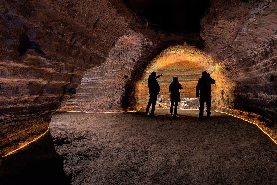 Three people stand in one of the caves at Hella.