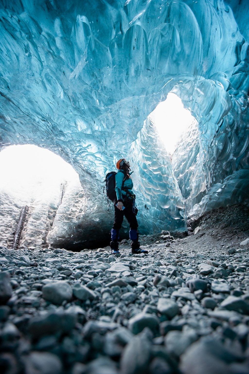 Traveler gazing up at sculpted blue ice in the depths of Iceland’s Sapphire Ice Cave.