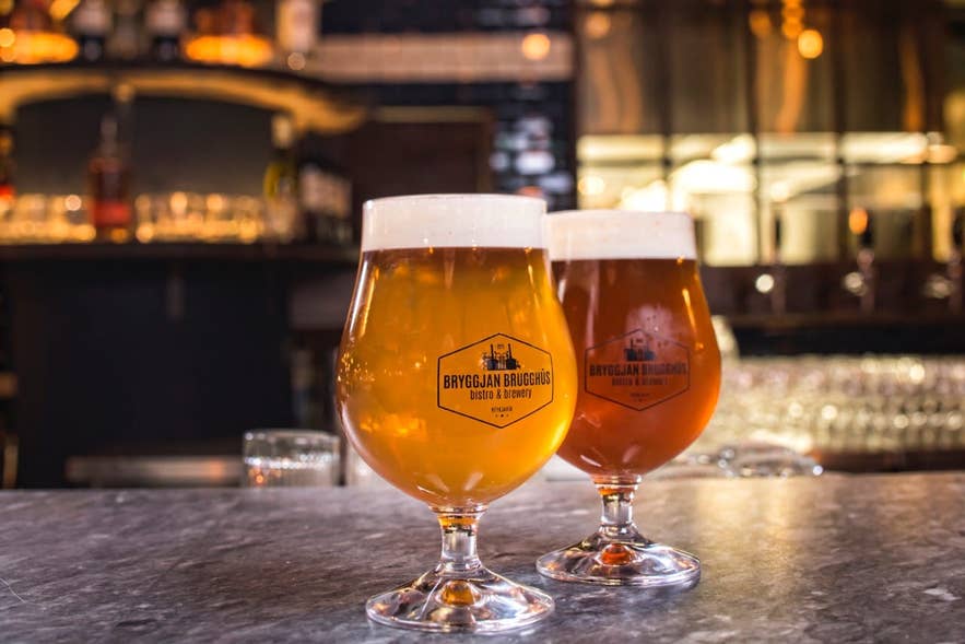 Two tulip glasses of Icelandic beer, one pale and one amber, on a bar