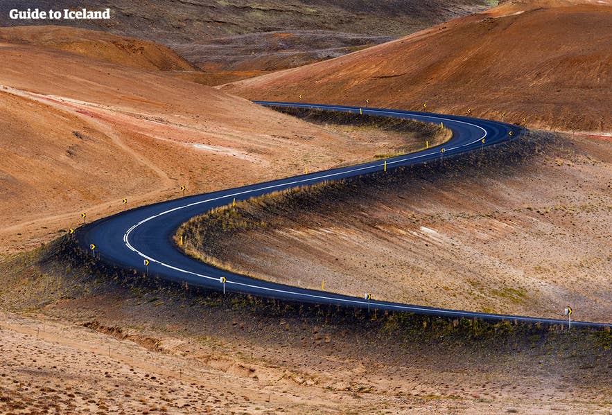A well-maintained paved road curving through the Icelandic countryside