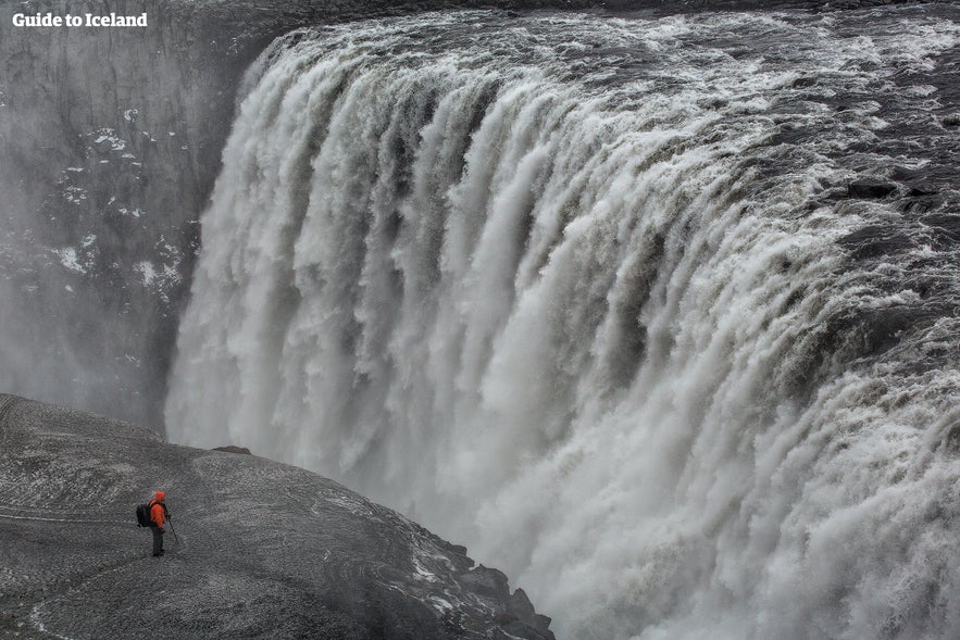 Hiker at Dettifoss Waterfall in North Iceland showing why Iceland is worth visiting for powerful natural sights.