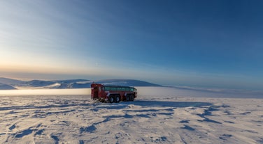 A red monster truck is seen parked on the ice.