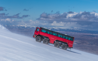 Ein großer roter Truck fährt auf den Langjökull-Gletscher.