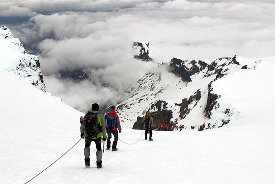 A row of hikers walking on the snow and ice on the Hrutfjallstindar mountain.