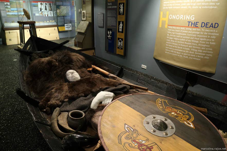 Recreated Viking boat burial with shields and grave goods at an Icelandic history museum.