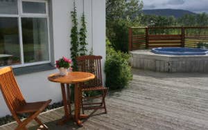 The outside area at Jadar Farm with a wooden table and two chairs, and a hot tub in the background.