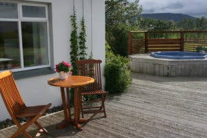 Uteområdet på Jadar Farm med et trebord, to stoler og boblebad i bakgrunnen.