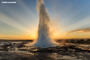 Gejzer Strokkur w Złotym Kręgu wybucha o zachodzie słońca.