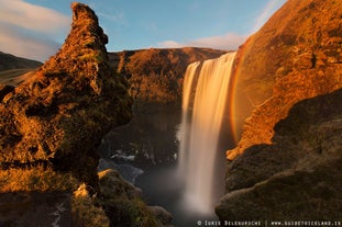 En el resplandor veraniego del sol, un arcoíris está constantemente presente en la niebla de la cascada de Skogafoss.