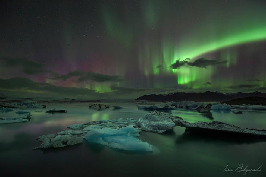 Northern lights above icebergs at Jokulsarlon Glacier Lagoon, best planned around Icelandic weather forecasts.