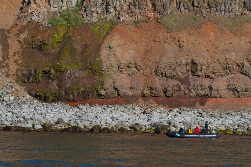 A boat in the sea below the cliffs of the Langanes peninsula.