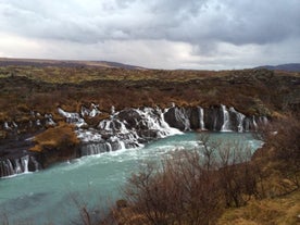 Hraunfossar-vattenfallen skapar ett ark av små rännilar som strömmar nerför lavaväggen.