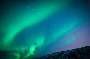 An ethereal sky of infinite stars and descending aurora lights in west Iceland's winter.