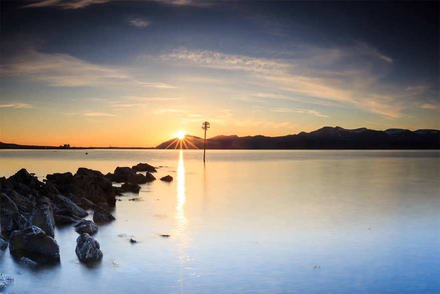 Sunset over the still water of Hvalfjordur with mountains on the far shore.