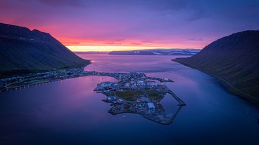 Una vista aerea della città costiera di Isafjordur, con il cielo illuminato di rosa e viola al tramonto