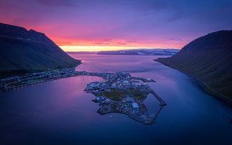 Vue aérienne de la ville côtière d'Isafjordur, avec le ciel illuminé de rose et de violet au coucher du soleil.