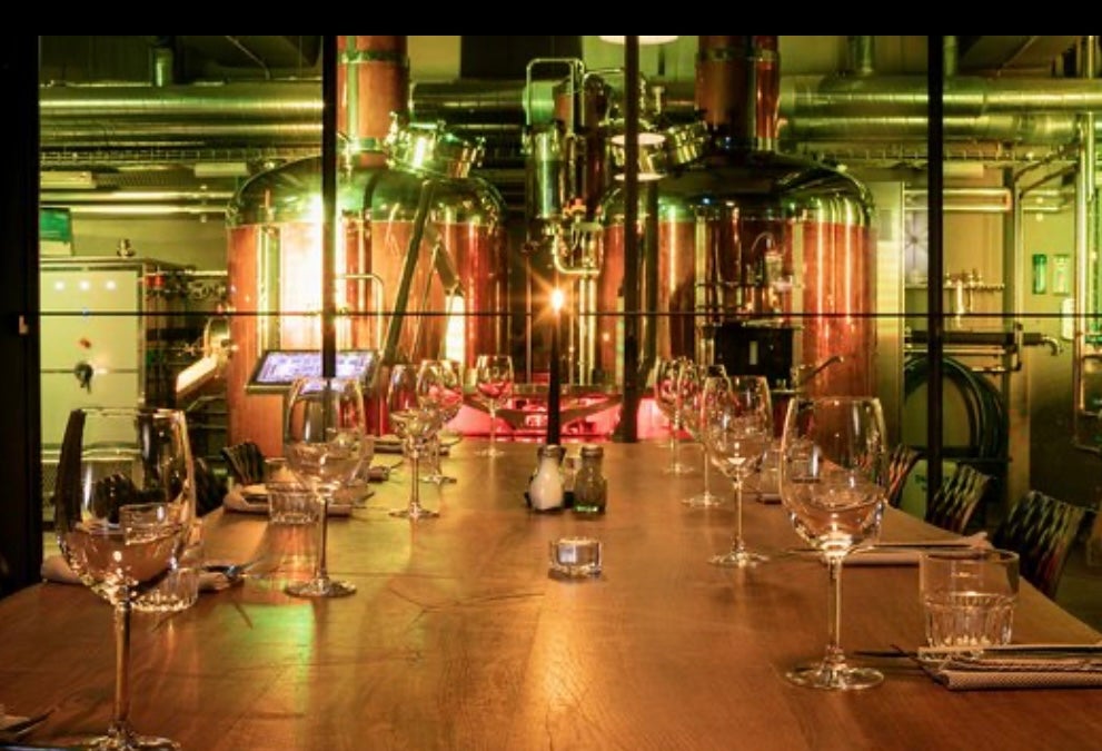 A table set with wine glasses and beer brewing facilities visible in the background at the Bryggjan Brugghus restaurant and brewery.