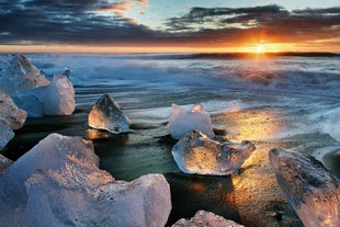 Il sole di mezzanotte splende sulla Spiaggia dei Diamanti nella costa meridionale islandese.