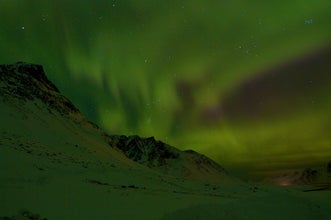 The sky veiled in green northern lights outside of Akureyri in North Iceland.