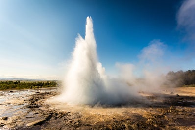 Gejzer Strokkur na trasie zwiedzania Złotego Kręgu wybucha, a wrząca woda wystrzeliwuje spod ziemi.