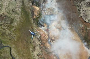 An aerial view of the Hengill geothermal area, with steam rising from the ground.