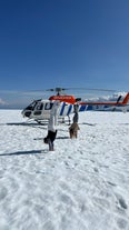 A helicopter and people in front of it on a glacier in Iceland.