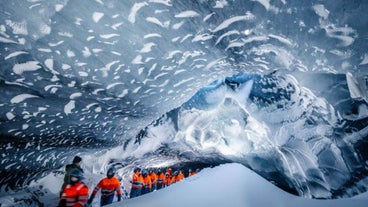 A guide leads travelers through an ice cave at Myrdalsjokull glacier.