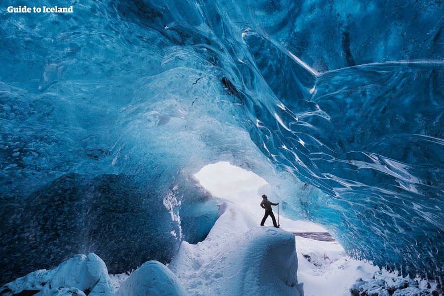 Traveler exploring the vivid blue Crystal Ice Cave inside Vatnajokull Glacier in Southeast Iceland.