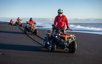 People ride ATVs along the jet black sands of the Solheimasandur beach.