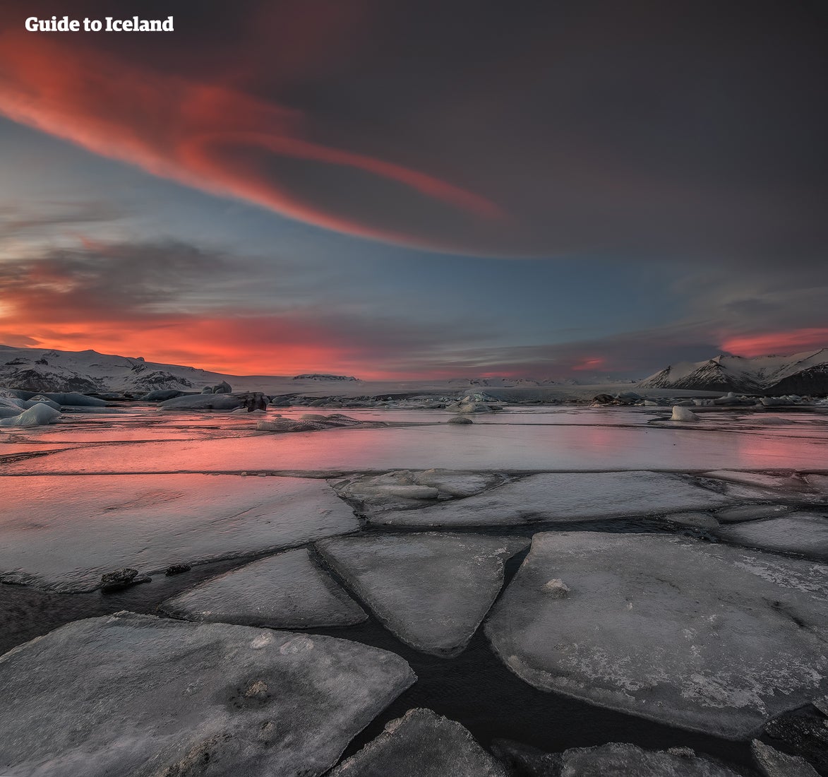 En isig lagun under en rosenröd himmel vid Jökulsárlón