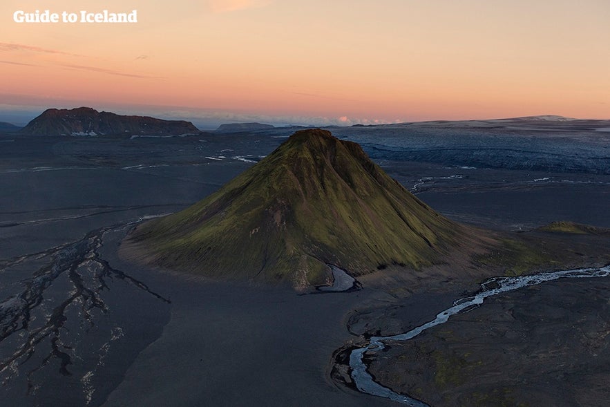 Laki volcanic cone in Iceland's Highlands at sunset, surrounded by dark lava fields and a winding river.