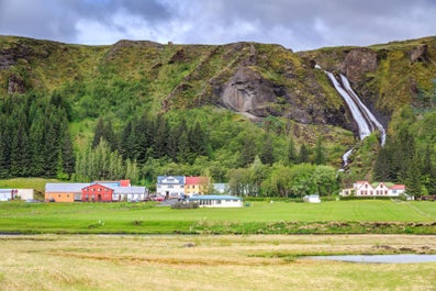 Kirkjubaejarklaustur village, with Systrafoss waterfall behind it during summer in Iceland.