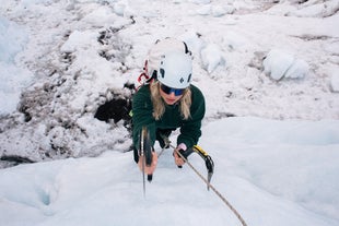 A person climbs an ice wall on an ice-climbing tour on the Falljokull glacier.