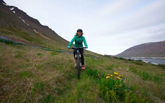 Una persona in bicicletta si avvicina verso la macchina fotografica nei Fiordi Occidentali, vicino a Ísafjörður.