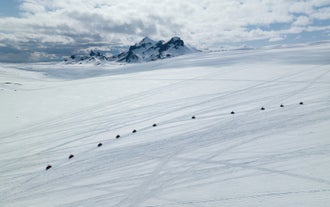 Eine Reihe von Schneemobilen auf einem verschneiten Gletscher in Island.