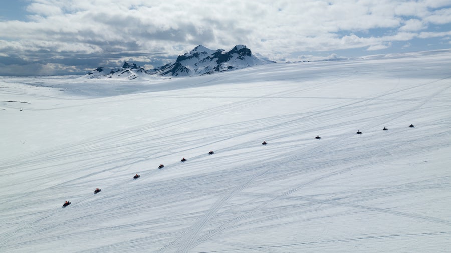 Una fila di motoslitte su un ghiacciaio innevato in Islanda
