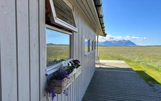 The outside of the Hestaland Horse Farm Cottage, with mountains and fields in the background.